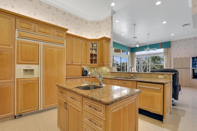 kitchen featuring hanging light fixtures, a kitchen island with sink, sink, and paneled refrigerator