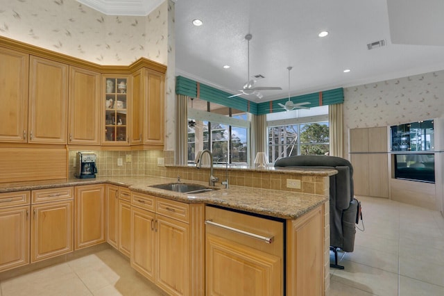 kitchen with ornamental molding, light stone countertops, and sink