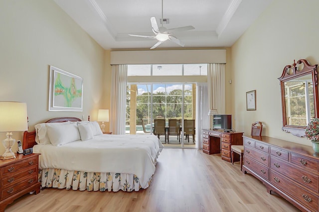 bedroom with ornamental molding, access to exterior, a raised ceiling, and light hardwood / wood-style floors