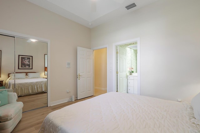 bedroom featuring connected bathroom, light wood-type flooring, and a closet