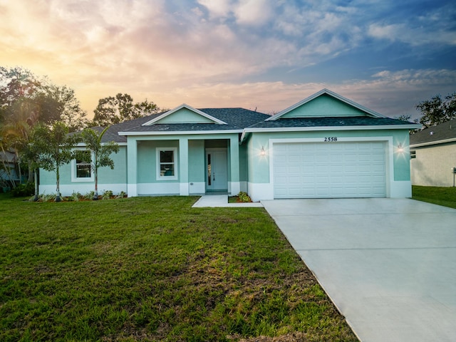 view of front of home with a garage and a lawn