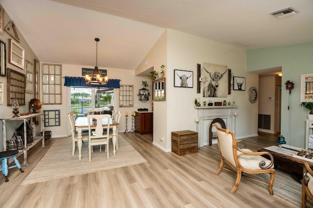 dining room featuring vaulted ceiling, an inviting chandelier, and light hardwood / wood-style flooring