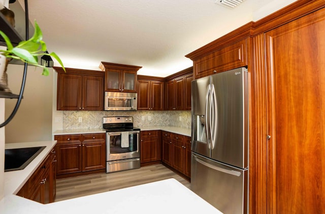 kitchen featuring stainless steel appliances, light hardwood / wood-style floors, sink, and backsplash