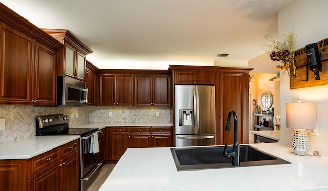 kitchen featuring tasteful backsplash, appliances with stainless steel finishes, kitchen peninsula, and sink