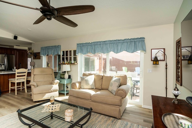 living room featuring vaulted ceiling, ceiling fan, and light hardwood / wood-style flooring