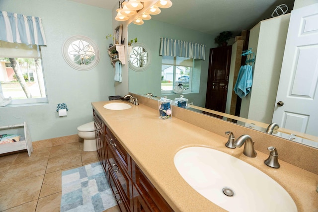 bathroom with tile patterned flooring, vanity, a healthy amount of sunlight, and toilet