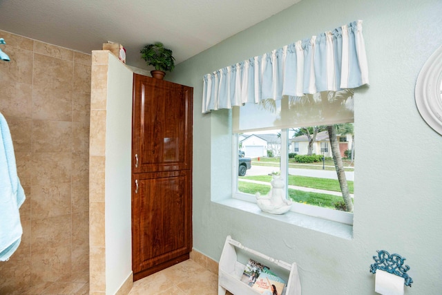 bathroom with tile patterned flooring and a tile shower