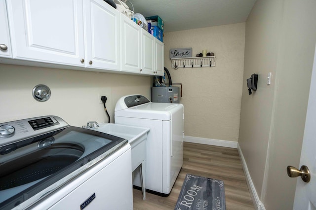 clothes washing area with cabinets, wood-type flooring, washer and clothes dryer, and water heater