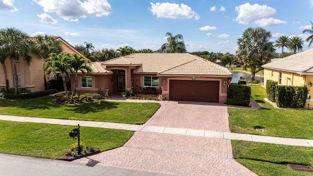 view of front of property with a garage, a water view, and a front lawn