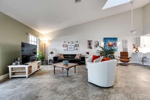 living room with a skylight, high vaulted ceiling, and ceiling fan