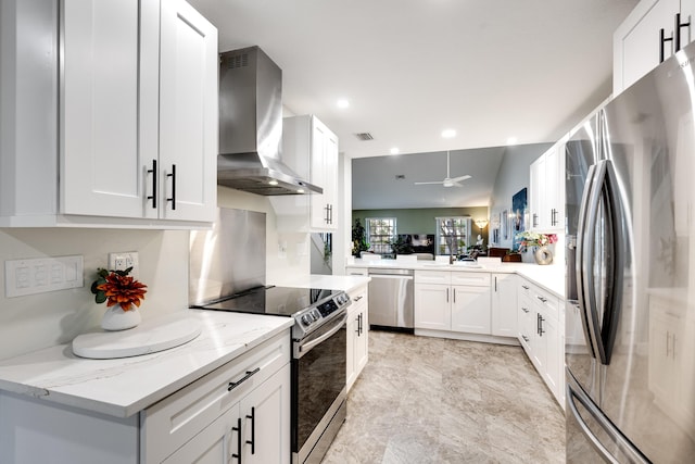 kitchen with wall chimney range hood, ceiling fan, white cabinetry, stainless steel appliances, and light stone counters