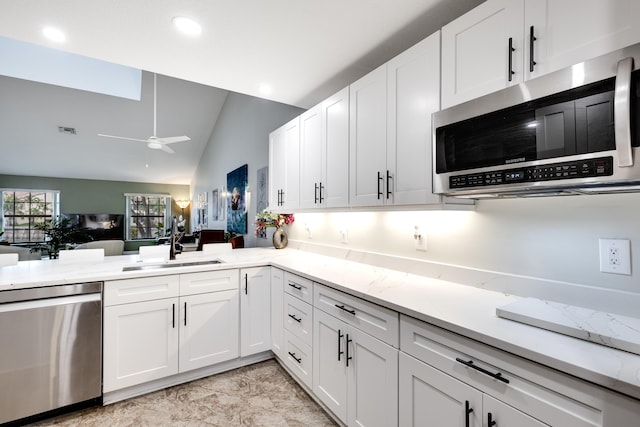 kitchen with sink, vaulted ceiling, stainless steel appliances, and white cabinets