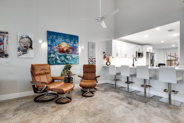 sitting room with a towering ceiling and ceiling fan