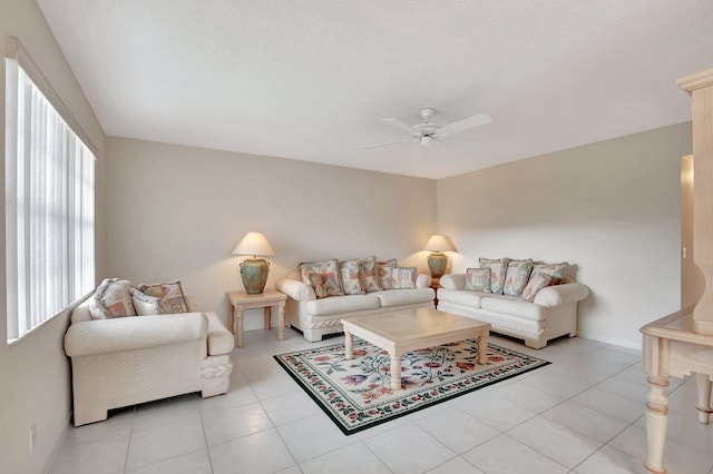 living room with light tile patterned floors, baseboards, a textured ceiling, and a ceiling fan