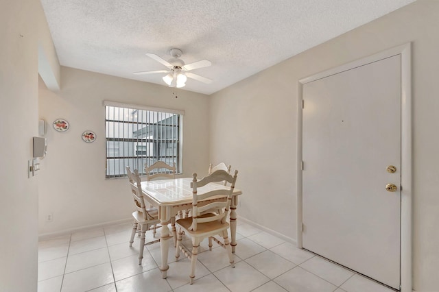 tiled dining area with ceiling fan and a textured ceiling