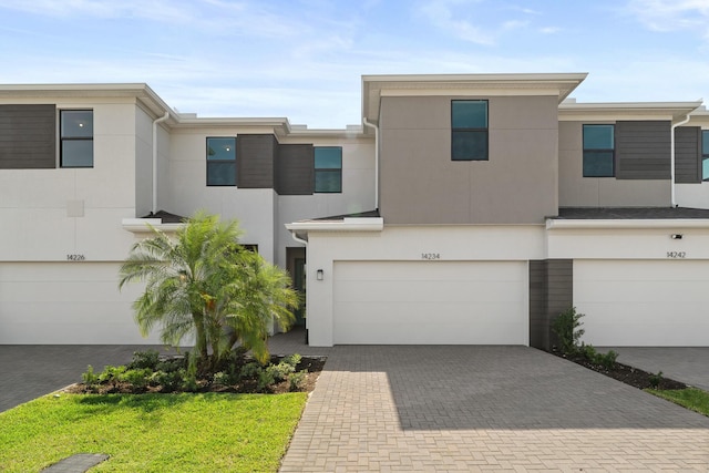 townhome / multi-family property featuring an attached garage, decorative driveway, and stucco siding