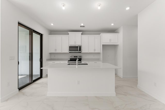 kitchen featuring a kitchen island with sink, stainless steel appliances, white cabinets, marble finish floor, and light countertops