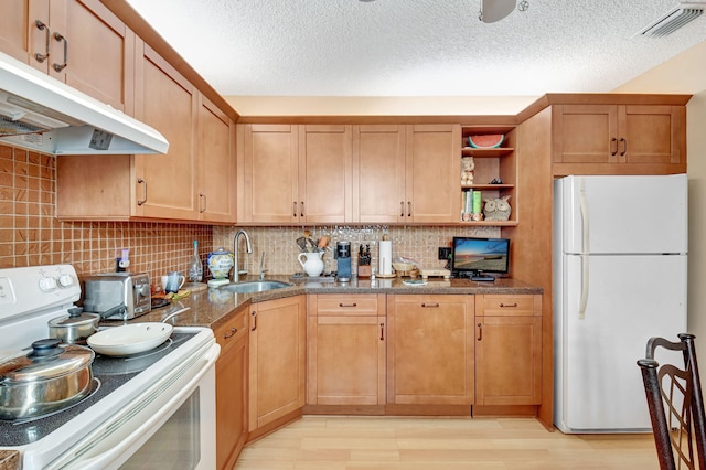 kitchen with sink, white appliances, dark stone countertops, tasteful backsplash, and light hardwood / wood-style floors