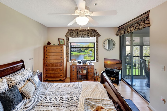 bedroom featuring ceiling fan, access to outside, light hardwood / wood-style floors, and a textured ceiling