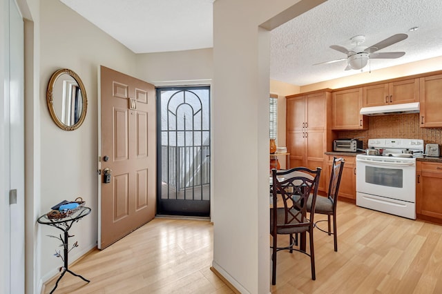 kitchen featuring white range with electric stovetop, decorative backsplash, ceiling fan, a textured ceiling, and light hardwood / wood-style flooring