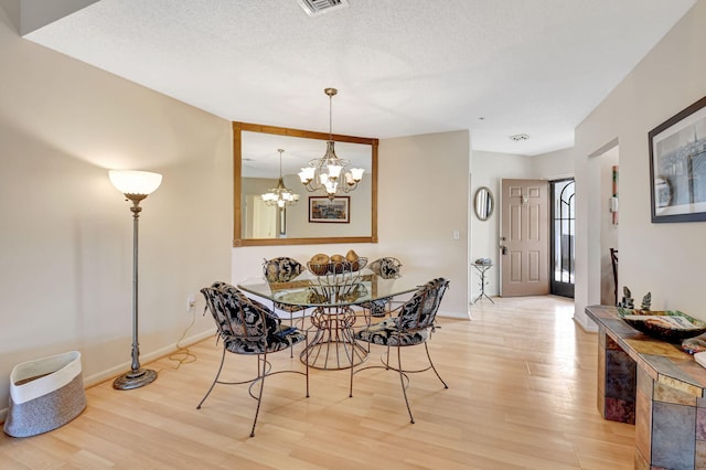 dining room featuring a chandelier, hardwood / wood-style floors, and a textured ceiling