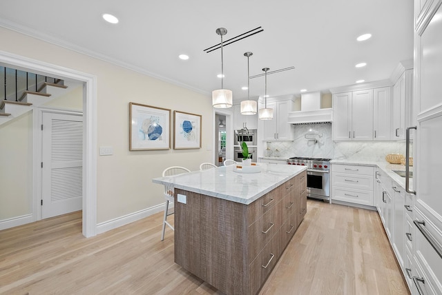 kitchen featuring premium range hood, a kitchen breakfast bar, appliances with stainless steel finishes, ornamental molding, and a center island