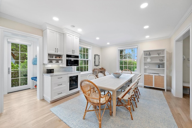 dining area featuring wine cooler, light wood-style flooring, recessed lighting, baseboards, and ornamental molding