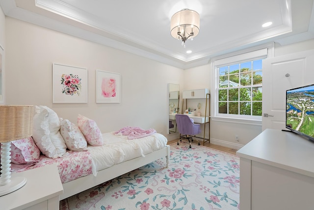 bedroom with light wood finished floors, a tray ceiling, ornamental molding, and baseboards