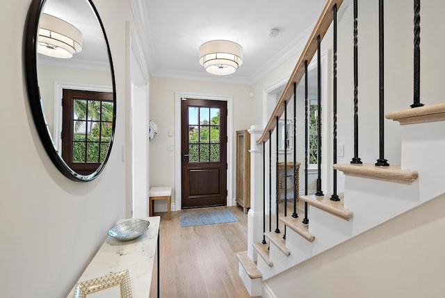 foyer featuring a healthy amount of sunlight, crown molding, stairway, and light wood finished floors