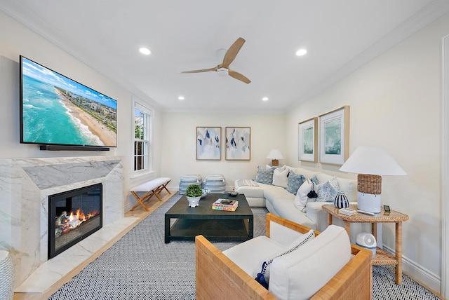 living area with crown molding, a fireplace, recessed lighting, a ceiling fan, and baseboards