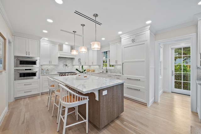 kitchen with premium range hood, backsplash, a sink, and white cabinetry