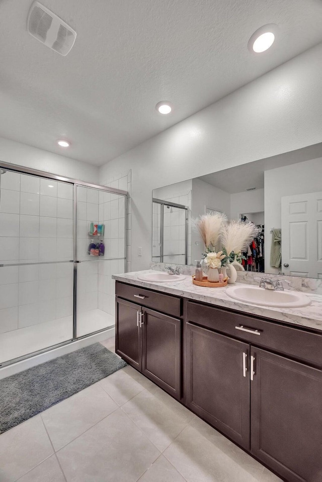 bathroom featuring tile patterned flooring, vanity, an enclosed shower, and a textured ceiling