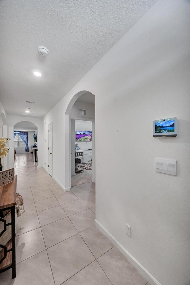 hall featuring light tile patterned floors and a textured ceiling