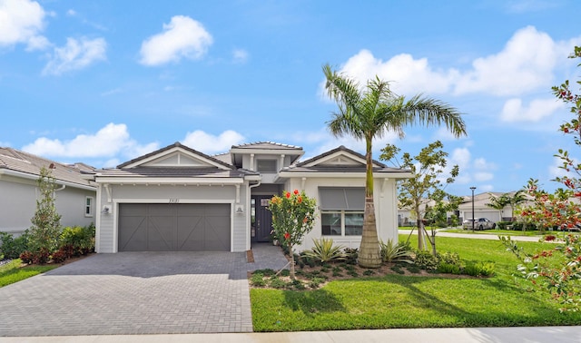 view of front of property with an attached garage, a tiled roof, decorative driveway, and a front yard