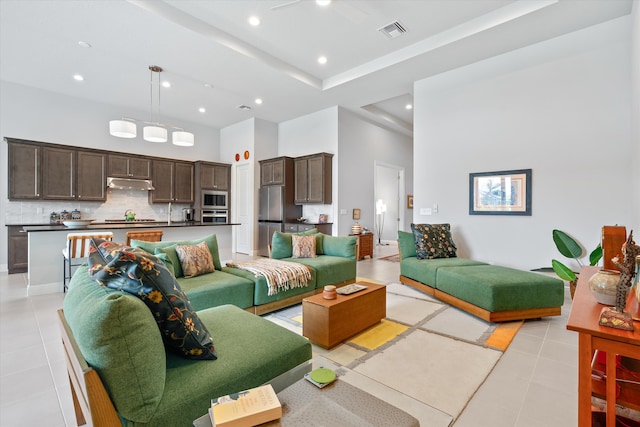 tiled living room with ceiling fan and a high ceiling