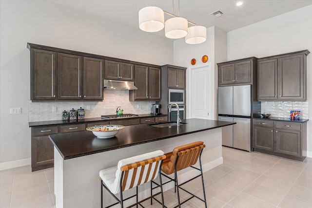 kitchen featuring pendant lighting, sink, stainless steel appliances, an island with sink, and light tile patterned flooring