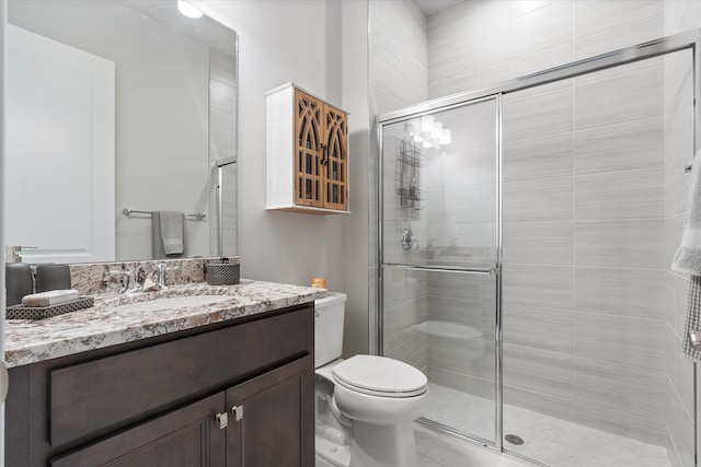 bathroom with vanity, toilet, and a shower with shower door