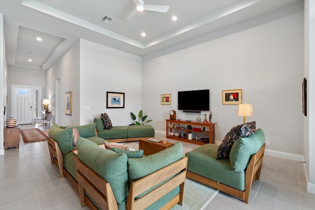 tiled living room featuring a raised ceiling and ceiling fan