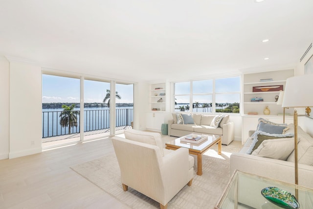 living room with built in shelves, light hardwood / wood-style floors, expansive windows, and a water view