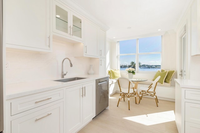 kitchen with sink, white cabinets, dishwasher, and a water view