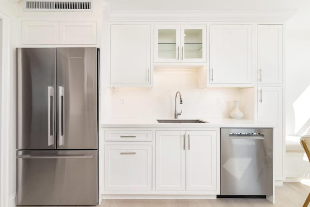 kitchen with sink, backsplash, white cabinets, and appliances with stainless steel finishes