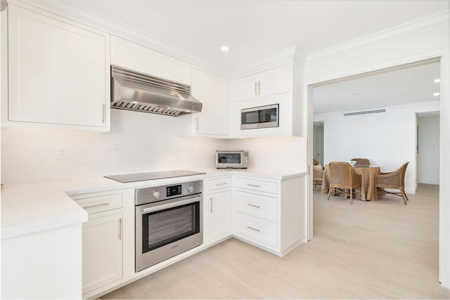 kitchen featuring white cabinetry, extractor fan, appliances with stainless steel finishes, and ornamental molding