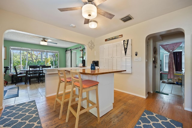 kitchen featuring arched walkways, visible vents, ceiling fan, and light wood-style flooring