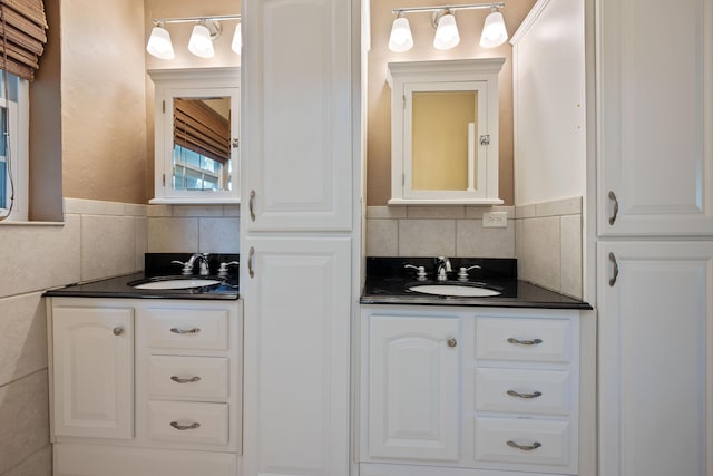 bathroom with two vanities, a sink, and tile walls