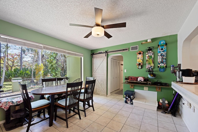 dining area with a barn door, visible vents, arched walkways, and a ceiling fan