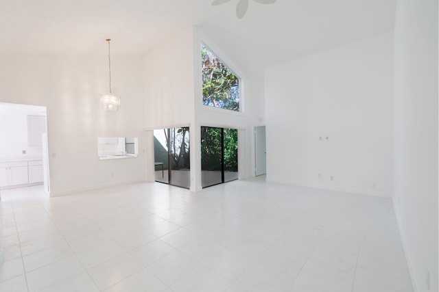 unfurnished living room featuring high vaulted ceiling, a notable chandelier, and baseboards