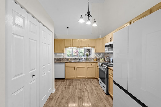 kitchen with sink, stainless steel appliances, light brown cabinets, decorative light fixtures, and light wood-type flooring