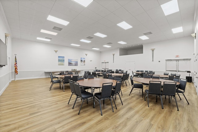 dining room with a paneled ceiling, a high ceiling, and light wood-type flooring