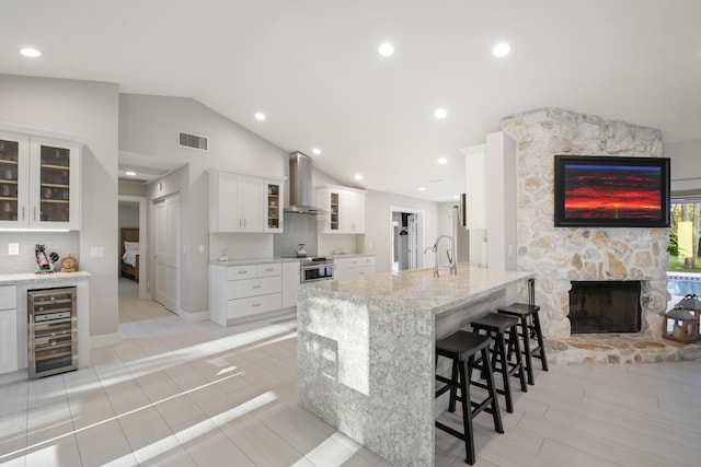 kitchen with visible vents, glass insert cabinets, white cabinets, beverage cooler, and exhaust hood