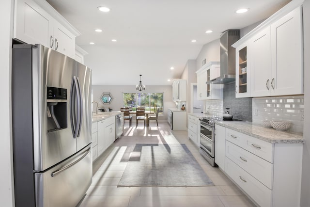 kitchen featuring stainless steel appliances, white cabinetry, glass insert cabinets, and wall chimney range hood